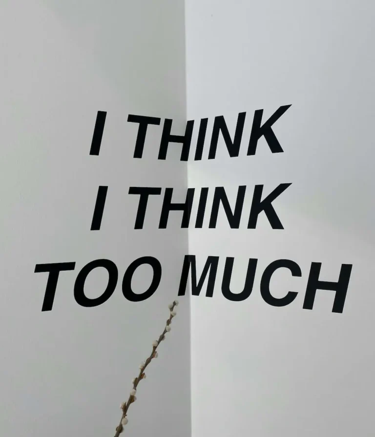 Minimalist black text on a white wall reading I think I think too much, capturing the overthinking patterns driven by subconscious anxiety.