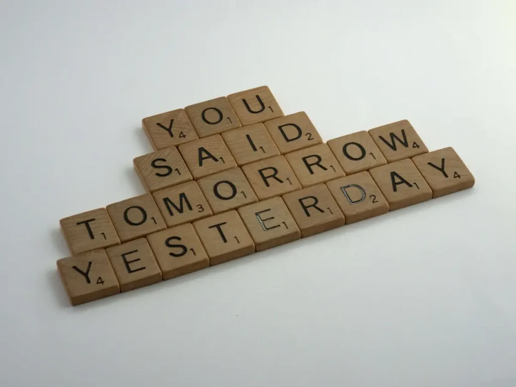 Scrabble letter tiles spelling out 'You said tomorrow yesterday' on a white background, illustrating the procrastination cycle and how to be disciplined.