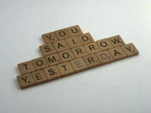 Scrabble letter tiles spelling out 'You said tomorrow yesterday' on a white background, illustrating the procrastination cycle and how to be disciplined.