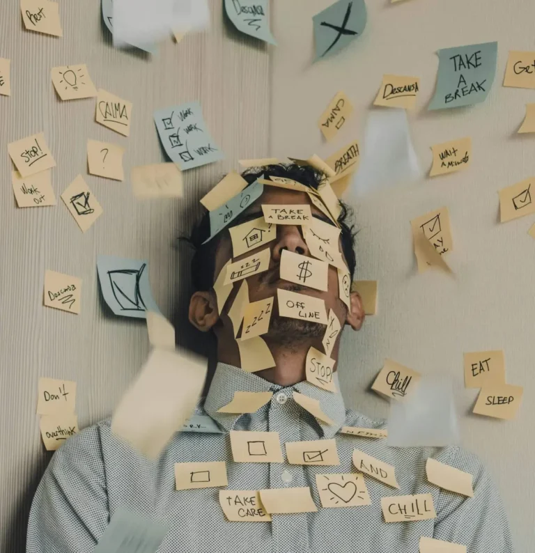 An exhausted man covered in sticky notes, illustrating the mental overwhelm of someone wondering why they can't stick to habits.