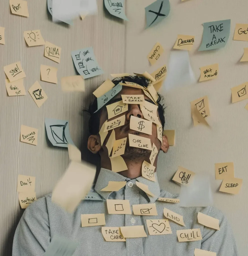 An exhausted man covered in sticky notes, illustrating the mental overwhelm of someone wondering why they can't stick to habits.
