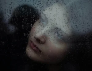 Person looking through a rain-covered window, representing the journey from automatic negative thoughts to more positive thinking.