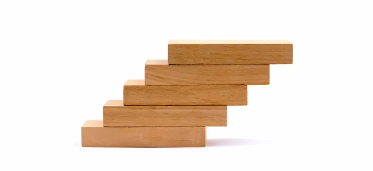 Wooden blocks stacked like steps, illustrating how habit stacking builds one routine on top of another.