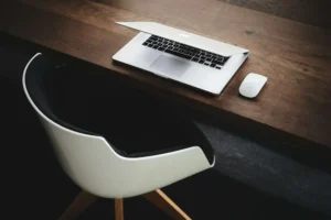 A clean, minimalist wooden desk with a half-closed laptop demonstrating distraction control and deep focus.