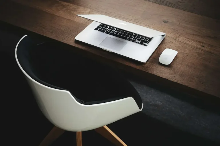 A clean, minimalist wooden desk with a half-closed laptop demonstrating distraction control and deep focus.