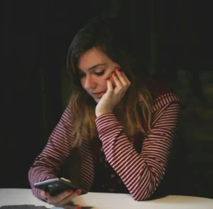Woman hesitating over her phone, representing the knowledge-action gap