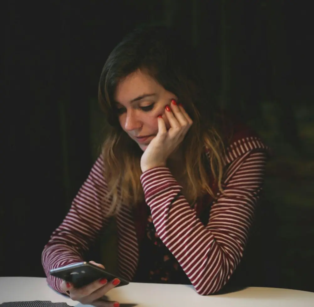 Woman hesitating over her phone, representing the knowledge-action gap