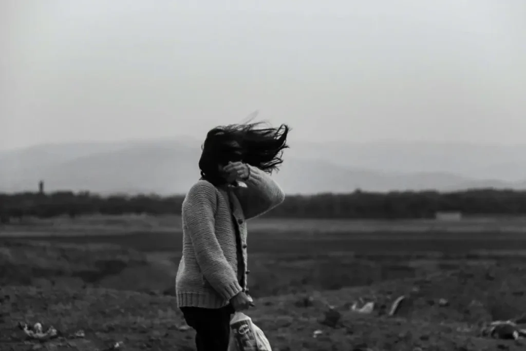 Woman walking through strong wind, representing mental toughness under pressure