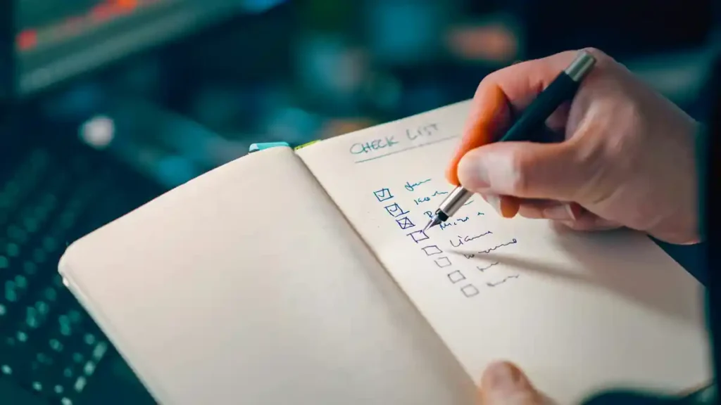 Person checking tasks in a notebook, representing consistency over perfection