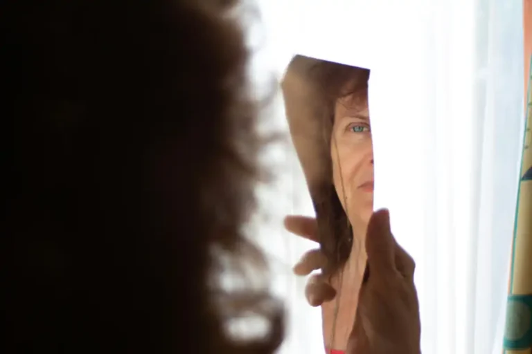 Woman looking at her reflection, representing how self-image affects behavior