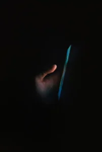 Person using a phone in the dark, representing a broken promise to stop scrolling and go to bed